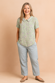 Zachtgroene blouse met korte mouwen en een lila blad- en bloemmotief in all-over print, afgewerkt met een ronde kraag.