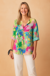 Kunstzinnige blouse met aquarel-achtige bloemenprint in felle kleuren zoals neon roze, limegroen, blauw en geel. Voorzien van een enkele houten knoopsluiting.
