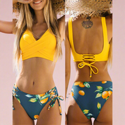 Bikini met gele twist-top en donkerblauwe slip met vrolijke sinaasappelprint en vetersluiting op de rug.