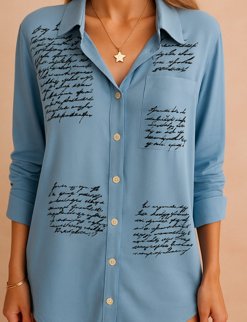 Lichtblauwe blouse met zwarte handgeschreven tekstaccenten, klassieke kraag en lange mouwen.