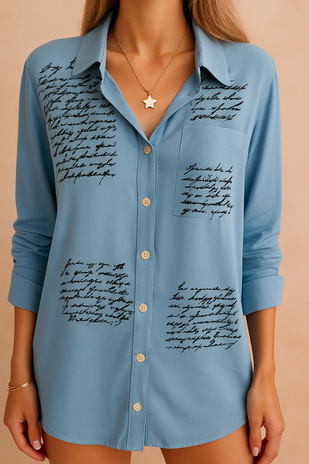 Lichtblauwe blouse met zwarte handgeschreven tekstaccenten, klassieke kraag en lange mouwen.