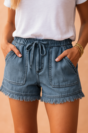 Blauwgewassen high-rise denimshorts met rafelzoom, oversized opgestikte voorzakken en verstelbare tailleband met trekkoord—de perfecte mix van comfort en casual stijl.