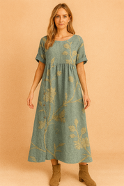 Blauwgroene linnen jurk met gouden geborduurde bloemenprint en knoopdetail aan de zijkant.