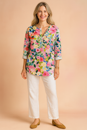 Linnen blouse met driekwartmouwen en kleurrijke bloemenprint in roze, groen, geel en blauw op een lichte ondergrond. Voorzien van halve knoopsluiting en rechte zoom.