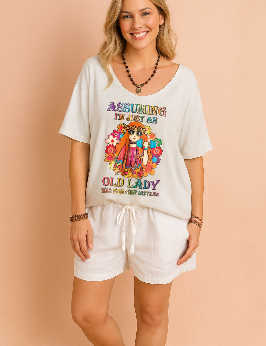 Crèmekleurig dames-T-shirt met diepe V-hals en opvallende kleurrijke hippieprint en tekst “Assuming I’m just an old lady”, vervaardigd van een luchtige stof en casual fit voor een relaxte zomerse look.