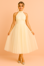 Crèmekleurige halterjurk met tule rok, elegante midi jurk met hoge halslijn en zachte ivoortint.
