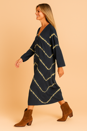 Donkerblauwe midi-jurk met lange mouwen, V-hals en volledige knoopsluiting, afgewerkt met diagonale tie-dye strepen in geel.