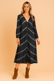 Donkerblauwe midi-jurk met lange mouwen, V-hals en volledige knoopsluiting, afgewerkt met diagonale tie-dye strepen in geel.