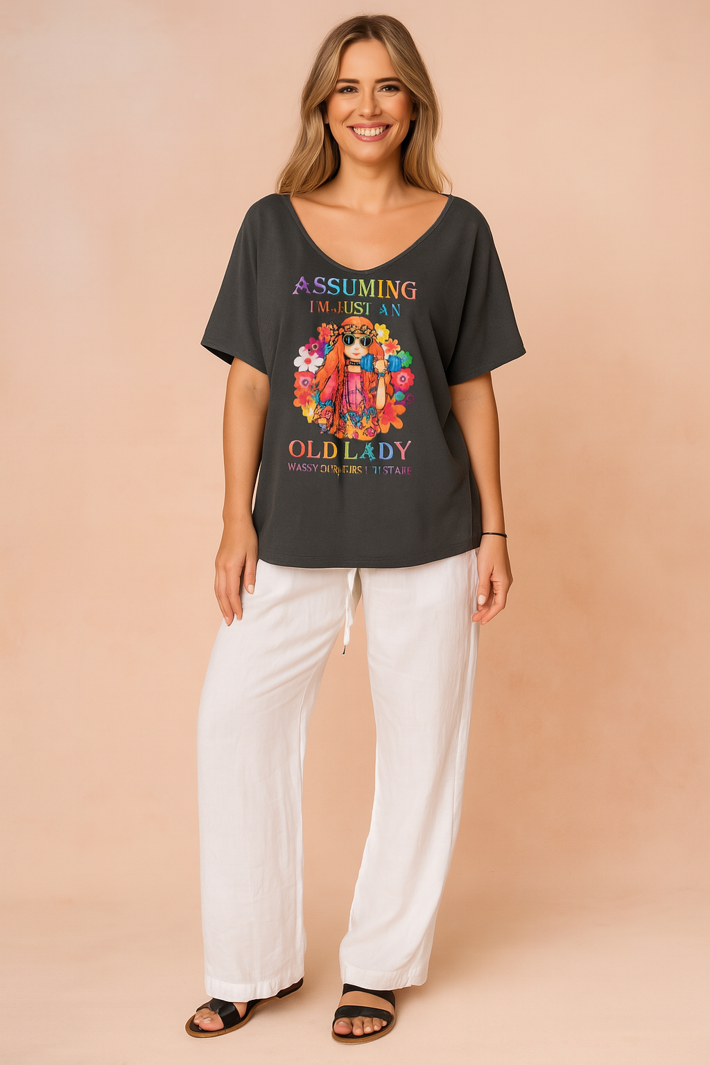 Donkergrijs dames-T-shirt met diepe V-hals, korte mouwen en kleurrijke hippie-print met de tekst “Assuming I’m just an old lady”, uitgevoerd in zachte, soepele stof voor een relaxte pasvorm.