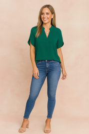 Donkergroene damesblouse met V-hals, elegante losse pasvorm en korte, aangeknipte mouwen. Gemaakt van een gladde, lichtgewicht stof.