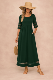 Donkergroene maxi jurk met transparante mouwaccenten en luchtige zoom, geschikt voor casual en chique outfits.