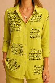 Felgroene blouse met zwarte handgeschreven print verspreid over de voorzijde, afgewerkt met een borstzakje en knoopsluiting.