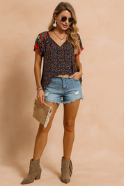 Boho bloemenblouse met V-hals, multicolor print en geborduurde mouwen, gecombineerd met gerafelde spijkershorts – ideaal voor zomerse festivals.