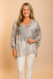Zachte grijze chiffon blouse met monochrome aquareleffect, losse vleermuismouwen en knoopsluiting.