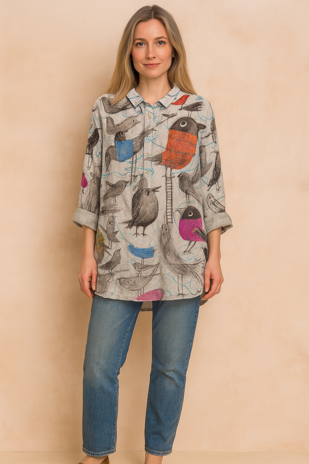 Oversized damesblouse met knoopsluiting, opgerolde mouwen en speelse meerkleurige vogelprint op een grijze ondergrond – perfect voor een casual artistieke look.