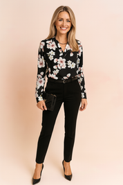 Zwarte damesblouse met lange mouwen, witte en blush bloemenprint en V-halsuitsnijding – ideaal voor kantoor of avondkleding.