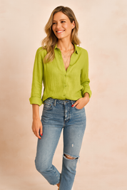Limoengroene linnen blouse met knoopsluiting en lange mouwen, gecombineerd met distressed denim jeans. De blouse heeft een losse pasvorm en zomerse uitstraling.
