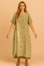 Lichtgroene linnen jurk met oranje bloemenprint, rechte pasvorm en knoopsluiting aan de zijkant.