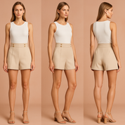 Elegante beige high-waisted shorts met decoratieve gouden knopen en plooien aan de voorkant, gecombineerd met een wit mouwloos crop top voor een chique zomerse outfit.