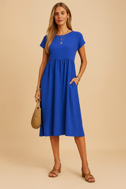 Kobaltblauwe midi jurk met korte mouwen en hoge taille, ideaal voor warme zomerdagen.