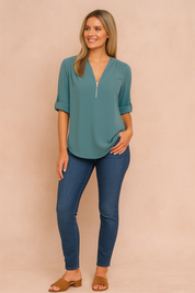 Effen blouse in zachtblauwe tint met gladde, lichte stof. Voorzien van een diepe V-hals met zilverkleurige halve rits en nonchalant opgerolde mouwen.