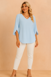 Lichtblauwe blouse met V-hals en driekwart vlindermouwen van soepele stof, ideaal voor een luchtige en elegante voorjaarslook.