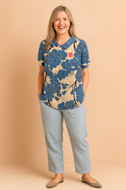 Beige linnen blouse met korte mouwen, opvallend grote blauwe bloemen en zwarte takken in een artistieke all-over print, voorzien van rood vierkant detail op de borst.