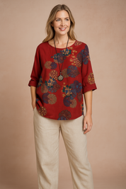 Ruimvallende rode blouse met ronde hals en opgerolde mouwen, met abstracte bloemenmedaillonprint in aardetinten en marineblauw. Perfect voor casual en boho-geïnspireerde outfits.