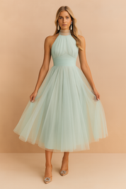 Mintgroene halterjurk met tule rok, frisse midi zomerjurk met hoge halslijn en luchtige uitstraling.