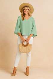 Mintgroene V-hals blouse met brede vlindermouwen en losse pasvorm, perfect voor een zomerse casual outfit.