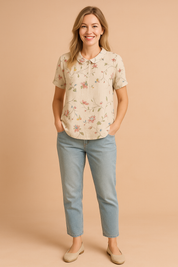 Beige blouse met korte mouwen en subtiel gebloemd borduursel in pastelkleuren, uitgevoerd in linnenstructuur en voorzien van een afgeronde kraag.