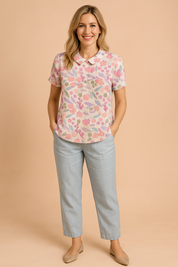 Linnenlook blouse met korte mouwen en opvallend bloemenpatroon in pastelroze, lila en zachtgroen, met ronde kraag en lichte textuur.