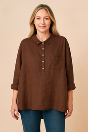 Bruine linnen blouse met klassieke kraag, halve knooppas en borstzak, gecombineerd met jeans voor een natuurlijke en tijdloze uitstraling.