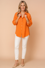 Losvallende oranje damesblouse met lange mouwen, doorknoopsluiting en zachte kreukstructuur in katoenmix.