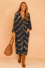 Oversized maxi jurk met tie-dye patroon in donkerblauw en beige, V-hals en knoopsluiting aan de voorkant.