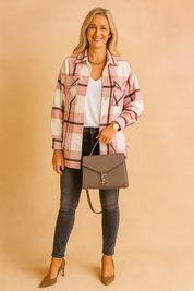 Damesoverhemd van roze flanel met wit en zwart ruitpatroon, opgestikte borstzakken en knoopsluiting, gedragen open over een witte top.