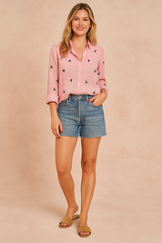 Roze linnen blouse met speelse zwarte zwaluwprint en opgerolde mouwen, zomers gecombineerd met een denim short.