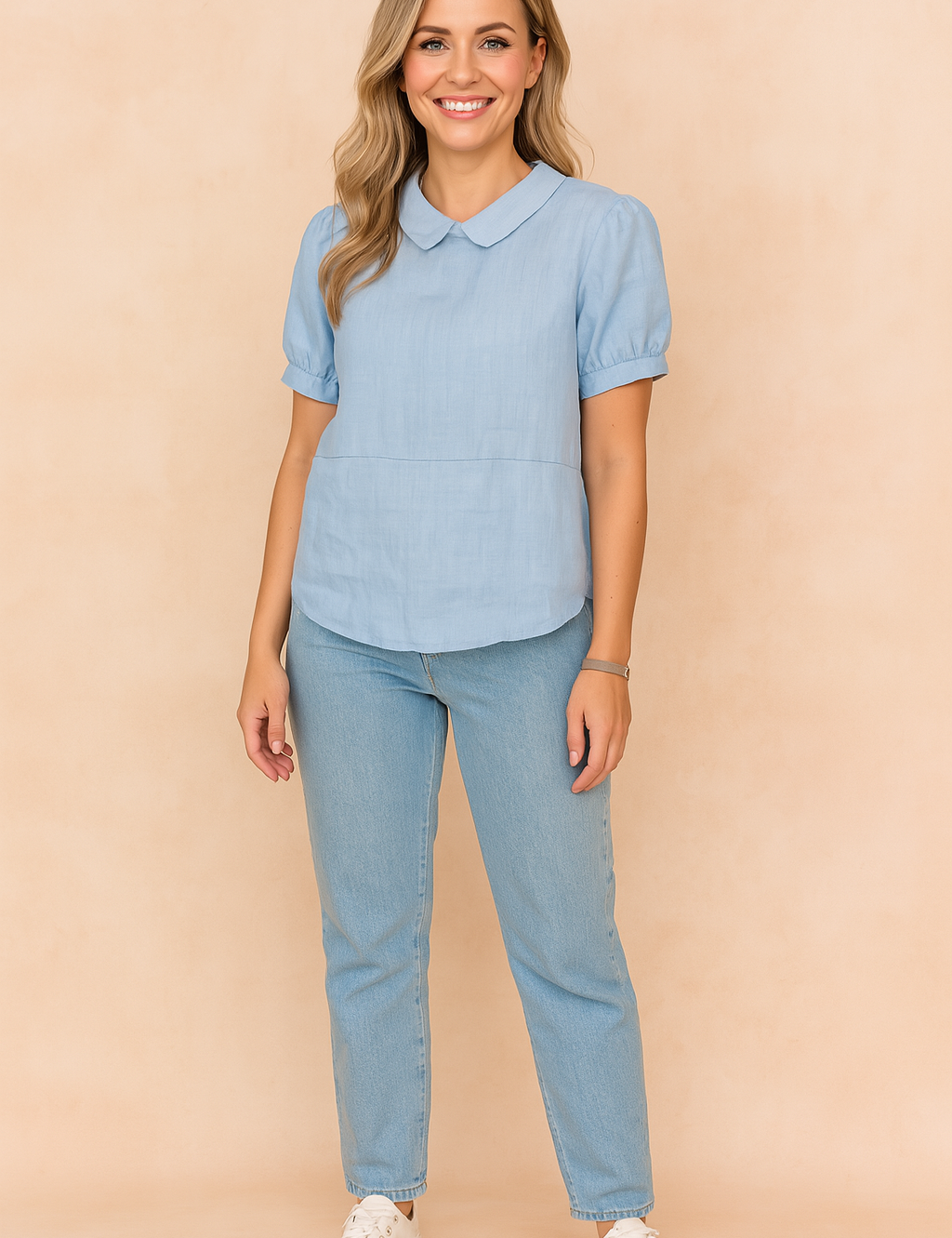 Lichtblauwe blouse met Peter Pan-kraag en korte pofmouwen, vervaardigd uit effen linnen-look stof.