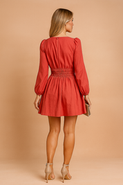 Rode mini jurk met lange mouwen en gesmokte tailleband, achterkant met knoopsluiting.