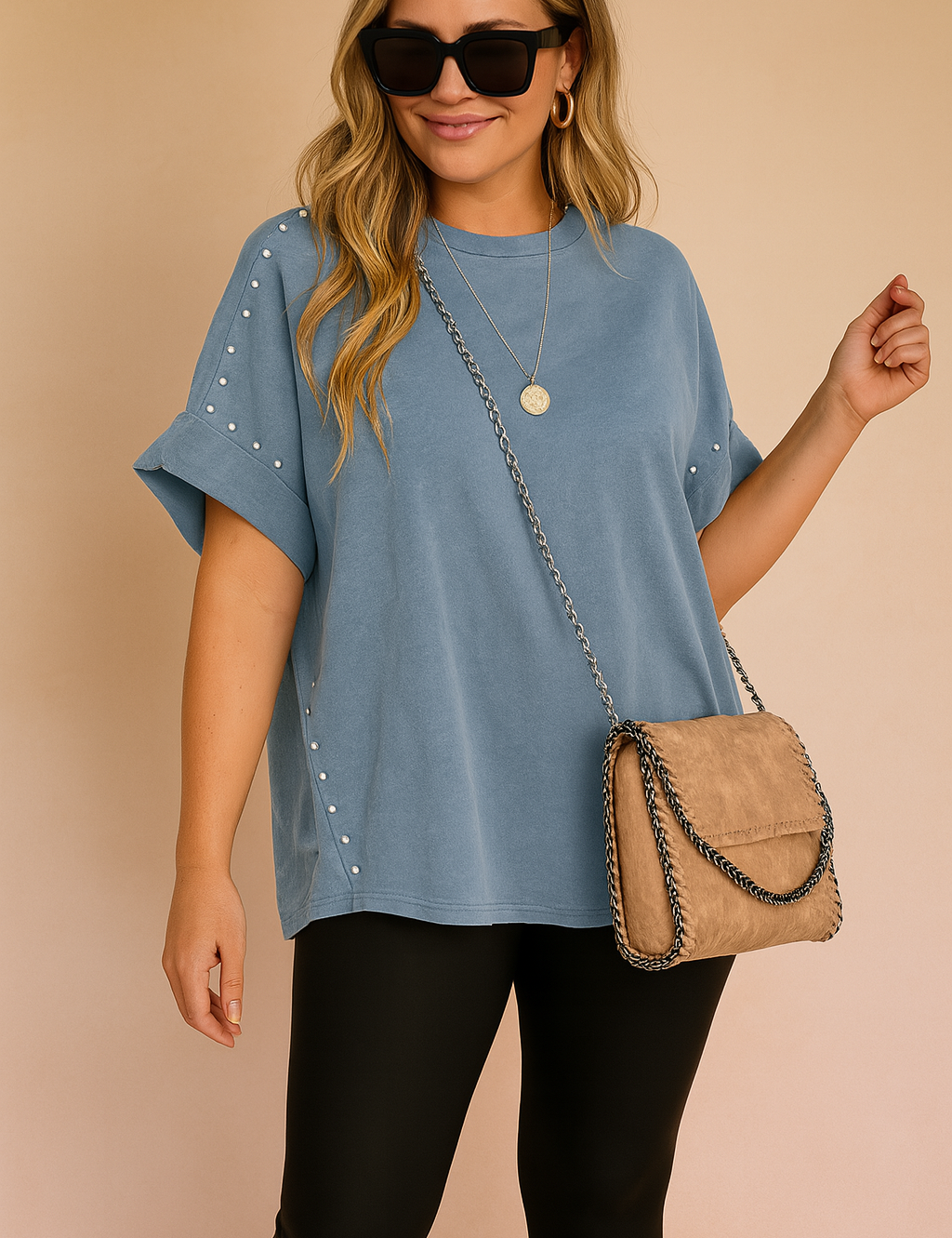 Blauwe casual tuniek met opgerolde mouwen en zilverkleurige studs aan de zijkanten en schouders.