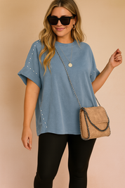 Blauwe casual tuniek met opgerolde mouwen en zilverkleurige studs aan de zijkanten en schouders.