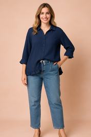 Donkerblauwe damesblouse met knoopsluiting, driekwartsmouwen en asymmetrische rufflezoom, gemaakt van luchtige, effen stof.