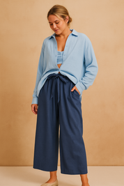 Lichtblauwe damesblouse in luchtige crinkle-stof met lange mouwen, knoopsluiting en ontspannen pasvorm, ideaal voor gelaagde looks.