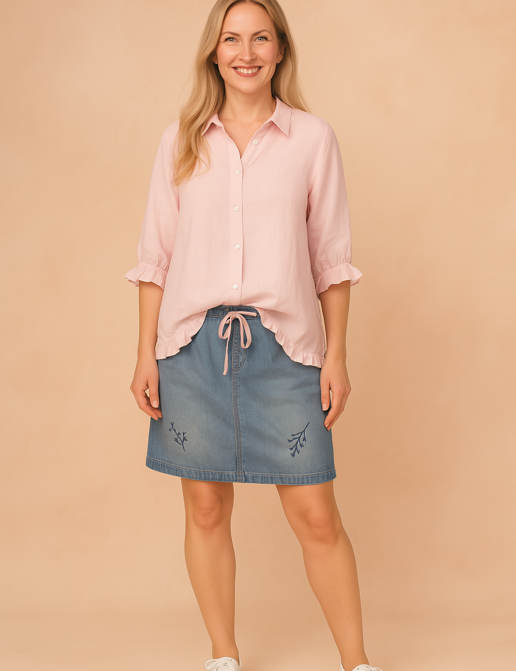 Lichtroze blouse met knoopsluiting, driekwartsmouwen en subtiele ruffle-afwerking aan de manchetten en zoom, in effen ademende stof.