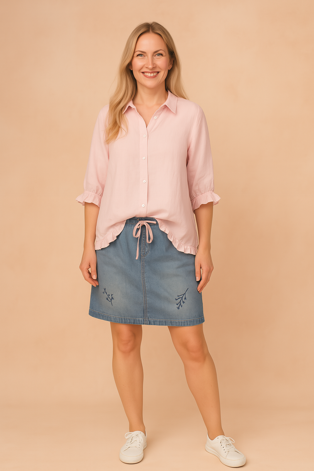 Lichtroze blouse met knoopsluiting, driekwartsmouwen en subtiele ruffle-afwerking aan de manchetten en zoom, in effen ademende stof.