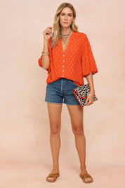 Oranje blouse met ingeweven stippenpatroon, V-hals, knoopsluiting en halflange mouwen, luchtig en speels design.