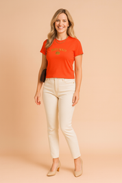 Oranje cropped dames-T-shirt met korte mouwen en ronde halslijn, bedrukt met groen MILANO-logo en decoratieve krans.