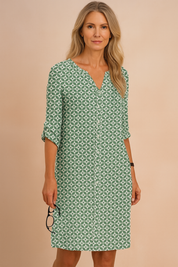 Dames overhemdjurk met groene en witte geometrische print, V-hals en opgerolde mouwen tot net boven de knie.