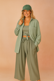 Saliegroene blouse in zachte, geribde crinkle-stof met lange mouwen, opgestikte borstzak en knoopsluiting, relaxed model.