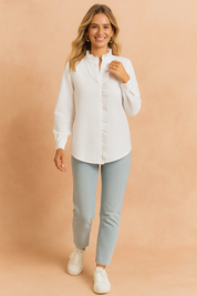 Witte blouse met lange mouwen, verborgen knoopsluiting en geplooide ruche-afwerking langs de kraag en sluiting, gemaakt van gestructureerde effen stof.